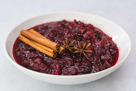 Cranberry sauce, cinnamon, anise star close up in a bowl on light backgroundの写真素材