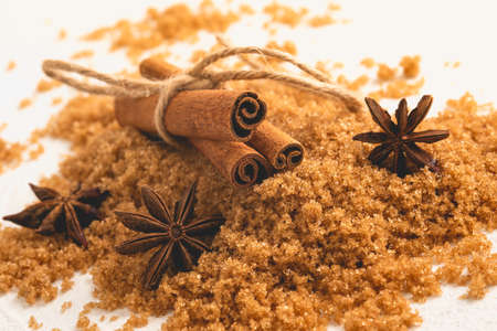 Brown sugar, anise star, and cinnamon sticks close up on white background