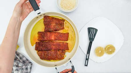 Smoked paprika roasted salmon  recipe. Fish slices close up on frying pan directly from above, woman...