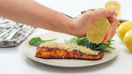Smoked paprika roasted salmon served with Parmesan cheese, spinach and lemon slices close up on a...
