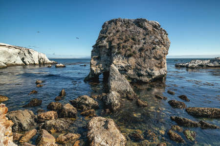 Rocky cliffs at low tide and clear blue sky on backgroundの写真素材
