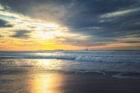 Tropical beach sunset. Stormy sea with huge waves and dramatic cloudy sky on background
