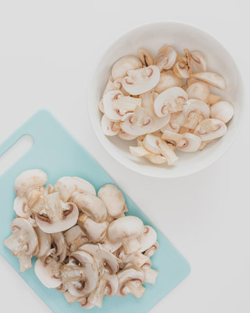 Fresh raw  chopped organic white mushrooms close up on cutting board on white background,flat lay, vertical bannerの写真素材