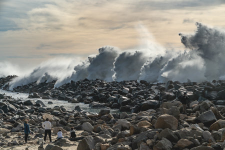 Morro Bay, California, USA- January 5, 2021  Rocky beach and stormy Pacific ocean at high tide. People on the beach enjoying viewのeditorial素材
