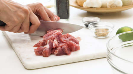 Chopped pork. Chef cutting meat on a marble cutting board close up on white background