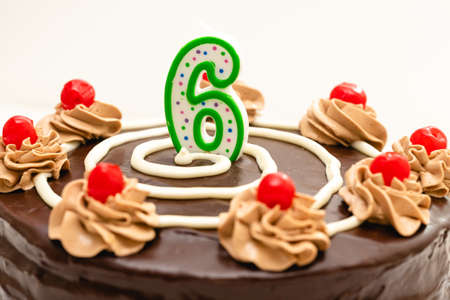 Birthday chocolate cake with candle in the form of number Six. Homemade cake decorated with...