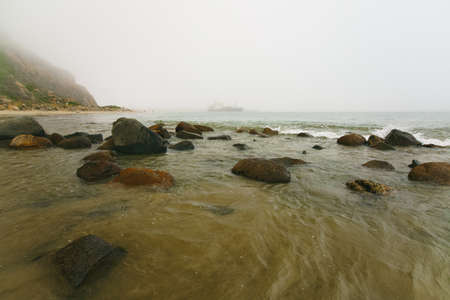 Rocky seashore at overcast foggy dayの写真素材