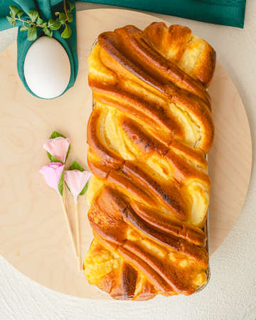 Baked yeast cake staffed with cream cheese, and white eggs close up on wooden serving board, flat lay, vertical banner. Brioche and eggs. Springtime, Easter conceptの写真素材