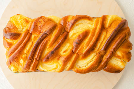 Baked yeast swirl cake, traditional French Brioche, staffed with cream cheese close up on wooden serving board, flat layの写真素材