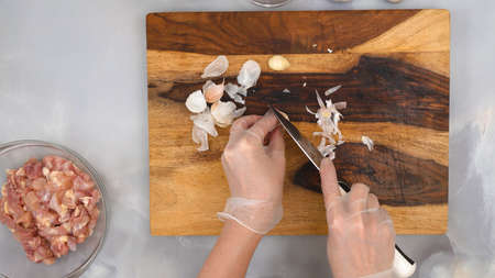 Woman hands peeling garlic, close up view from above. Sour cream chicken paprika recipe, step by step cooking process, part of seriesの写真素材