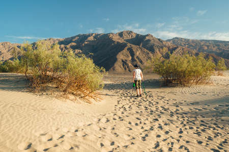 Death Valley, California, USA - April 14, 2021.   Mature woman with bottle of water and walking cane hiking in desert. Mesquite Sand Dunes in Death Valley National Park, Californiaのeditorial素材