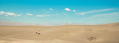 Death Valley, California, USA - April 14, 2021.   Desert hiking. Tourists hiking among sand dunes....