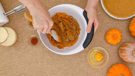 Mixing pumpkin puree and brown sugar in a bowl. Step by step pumpkin pie recipe, close up view from...