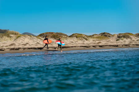 Morro Bay, California/USA-September 23, 2020  Friends, two young men, wearing in wetsuits with their surfboards walking on the beach.のeditorial素材