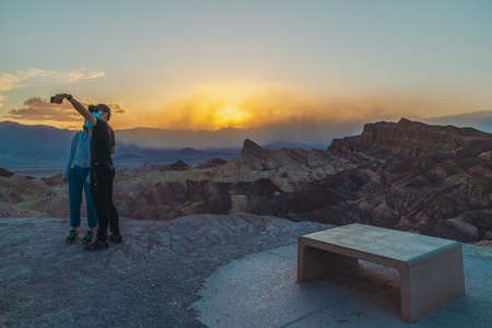 Death Valley, California, USA- April 14, 2021  Zabriskie point sunset,  one of the most popular spots in Death Valley National Park to see sunset. Tourists overlooking valley.のeditorial素材