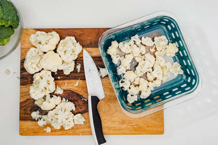 Cauliflower and broccoli close up on wooden cutting board directly from above on light grey backgroundの写真素材