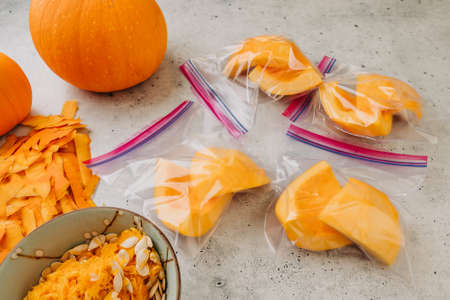 Fresh raw peeled pumpkin slices in zip lock bags close up, ready to be frozen