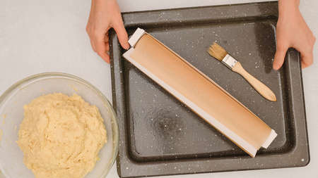 Pizza dough in a glass bowl, baking pan, and parchment paper close up on kitchen table. Step by step baking processの写真素材