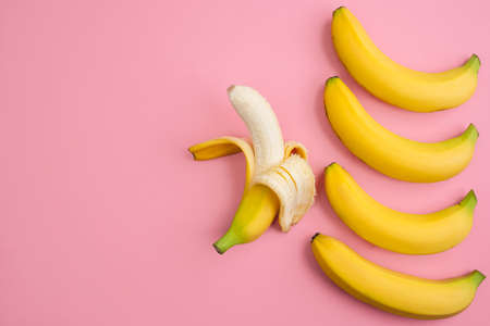 Bananas close up on light pink background with copy space for the text, flat lay. Seamless pattern bananas on a pink backgroundの写真素材