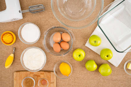 Apple cake with biscuit base recipe. Green apples, and ingredients for baking needs close up on kitchen tableの写真素材