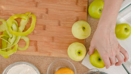 Apple cake with biscuit base recipe. Peeled green apples close up on a wooden board on rustic backgroundの写真素材