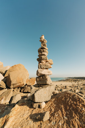 Pyramid of sea pebbles on a sunny rocky beach. Life balance and harmony concept, vertical banner