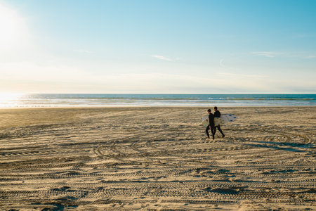 Oceano, California, USA -December 14, 2022. Wide sandy beach and surfers walking towards the ocean, a beautiful California seascape on a bright sunny dayのeditorial素材