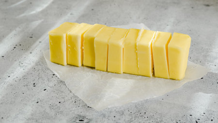 Cut block of butter on the kitchen table. Close-up view, gray stone background.の写真素材