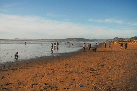 Cayucos, California, USA- December 25, 2022. Wide sandy beach and people walking along the shoreのeditorial素材