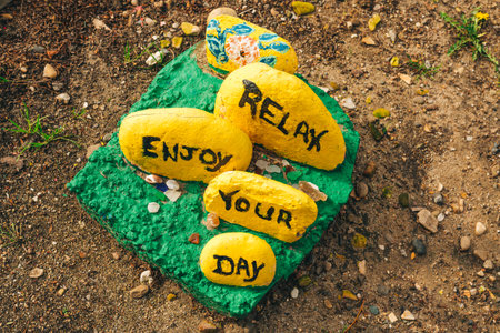 Avila Beach, California, USA - February 7, 2023. Relax, enjoy your day - painted colorful stones close-up on the ground - a nice idea to spread a joy and kindnessのeditorial素材