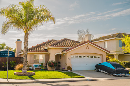 Santa Maria, California, USA - March 13, 2023. Beautiful houses with nicely landscaped front the yard in small town in California. Architecture, ornamental plants and flowers, palm trees, and cloudy sky in the backgroundのeditorial素材