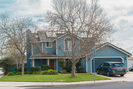 Santa Maria, California, USA - March 13, 2023. Beautiful houses with nicely landscaped front the yard in small town in California. Architecture, ornamental plants and flowers, palm trees, and cloudy sky in the backgroundのeditorial素材