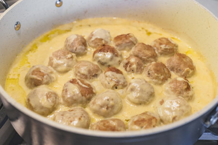 Sweadish meatballs in a creamy white sauce recipe. Meatballs close up on frying pan