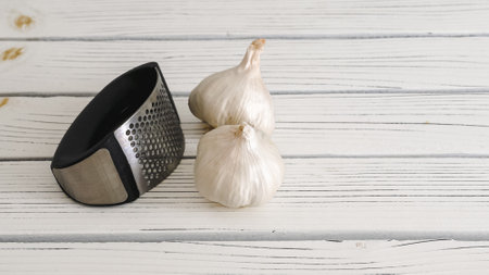 Garlic press and garlic cloves close-up on a white wooden backgroundの写真素材