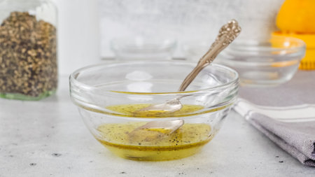 Lemon-olive oil salad dressing in a glass bowl close-up on the kitchen tableの写真素材