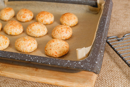 Freshly baked traditional Brasilian cheese bread close-up on the baking sheet on the kitchen table