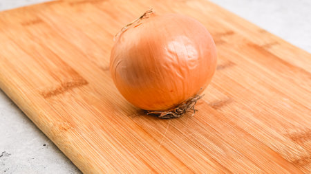 Peeling and cutting white onion on a cutting board. Vegetable soup recipe. Ingredients close-up on the kitchen tableの写真素材