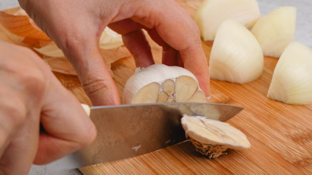 Peeling and cutting white garlic on a cutting board. Vegetable soup recipe. Ingredients close-up on the kitchen tableの写真素材