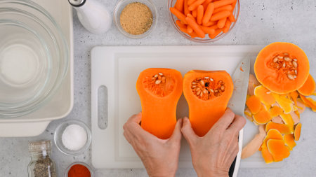 Butternut squash soup recipe, preparation process. Raw vegetables and spices close-up on the kitchen table, flat lay. Woman hands peeling squash, flat layの写真素材