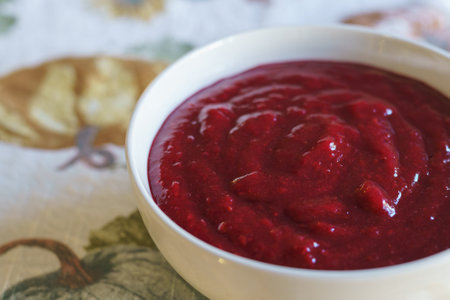 Cranberry sauce in a white bowl close-up on a tableの写真素材