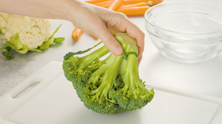 Broccoli, cauliflower, carrot close-up on a kitchen table. Fresh raw organic vegetables close-up on white background, woman hands. Cooking, preparation, recipeの写真素材