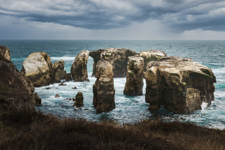 The rugged beauty of a rocky coastline meeting the vast expanse of the ocean under a dramatic sky, California Central Coastの写真素材