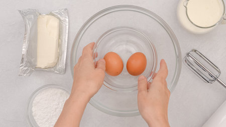 Arrangement of fresh ingredients, including cream cheese, eggs, whipped cream, and powdered sugar, baking process, woman handsの写真素材