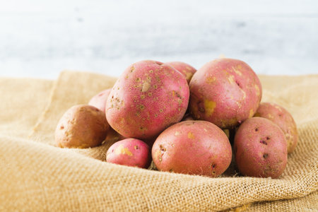 Red potatoes close-up. Fresh raw organic red potatoes close-up on a rustic background on a kitchen tableの写真素材