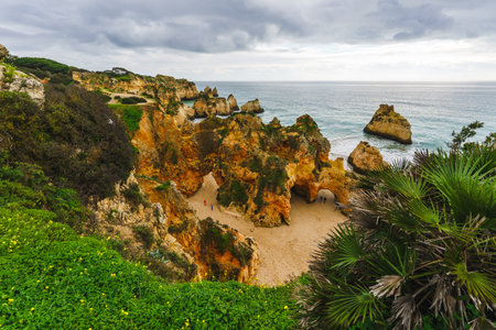 Rugged coastal vista with towering arches, hidden caves, crashing waves, and a brooding skyの写真素材