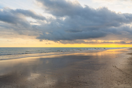 Sunset paints the sky with warm hues over a tranquil beach.の写真素材