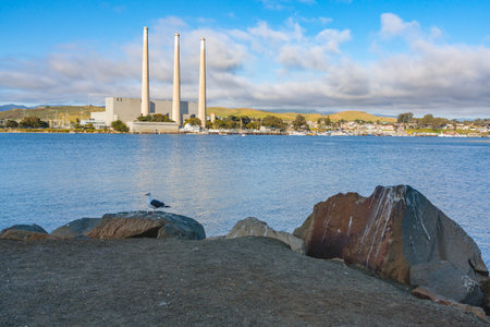 Morro Bay, California, USA - May 27, 2021  Rocky beach and old power plants whose three large smokestacks can be seen from anywhere in Morro Bay. Morro Bay State Park, California Central Coastのeditorial素材
