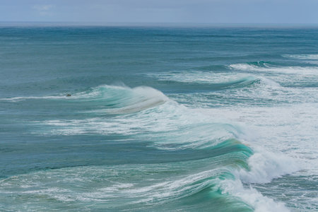 A lone surfer rides an immense wave showcasing the formidable surf Nazare is famous for. Portugal, Silver coastの写真素材