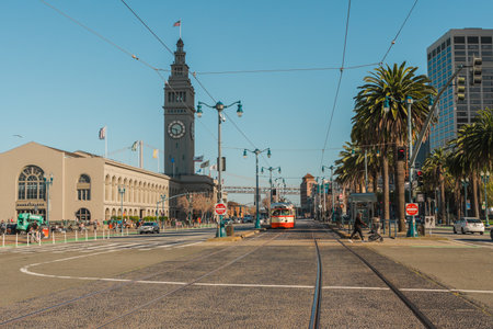 San Francisco, California, April 8, 2024. Streetcar tracks leading towards the Ferry Building clock tower, flanked by palm trees on The Embarcadero.のeditorial素材