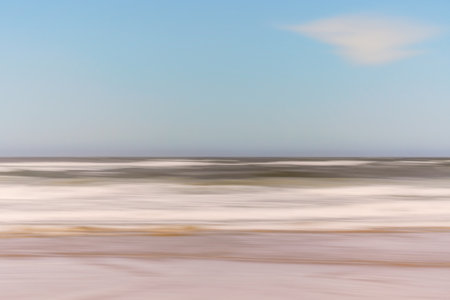An abstract view of ocean waves creates a blurred horizon with a soft blue sky.の写真素材